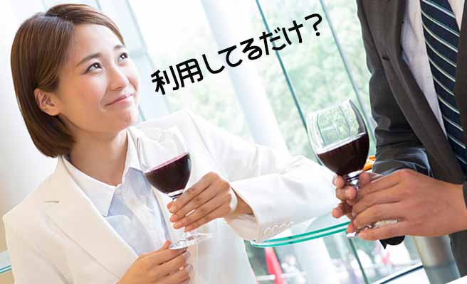 ワイングラスを持って立ちながら男性と会話する女性