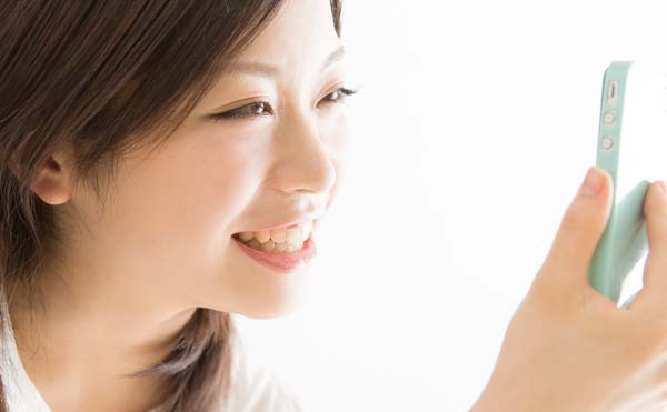笑顔でスマフォを見つめる女性