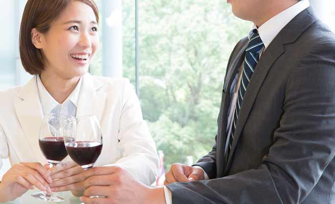 ワインを飲みながら男性と会話する女性