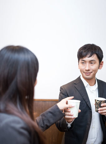 女性社員に飲み物を渡す不敵な笑顔の男性社員