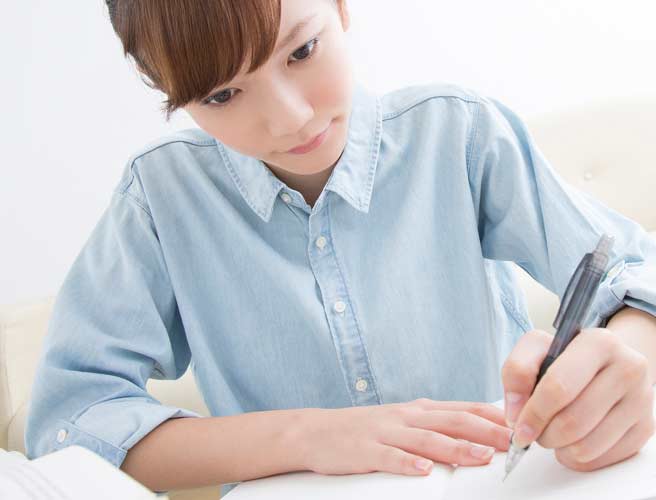 ノートに書き物をする女性