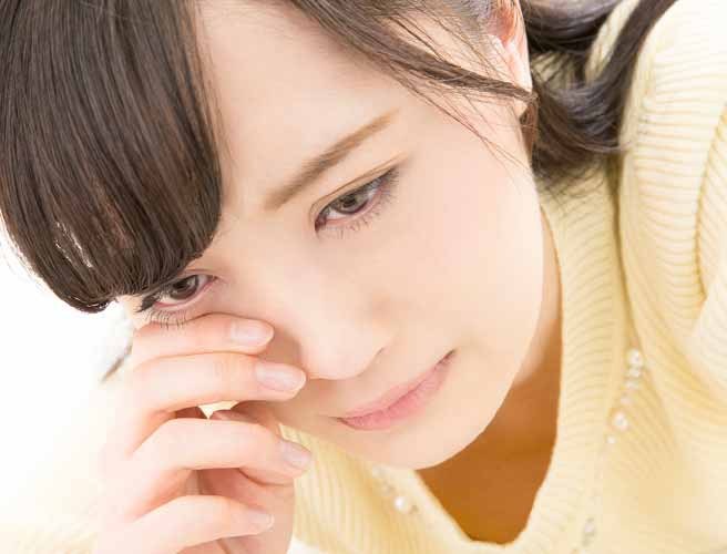 目の下をこする女性