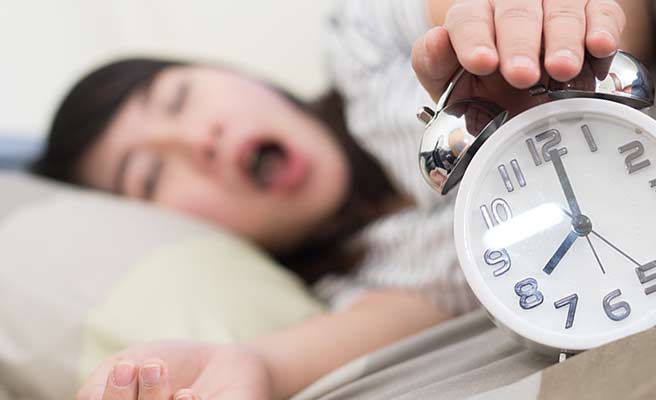 目覚まし時計を止める女性