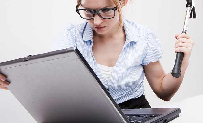 ノートパソコンに向かってハンマーを振り上げる女性