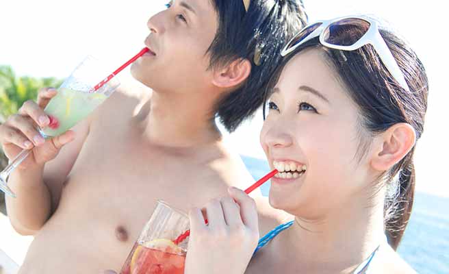 ビーチでジュースを飲むカップル