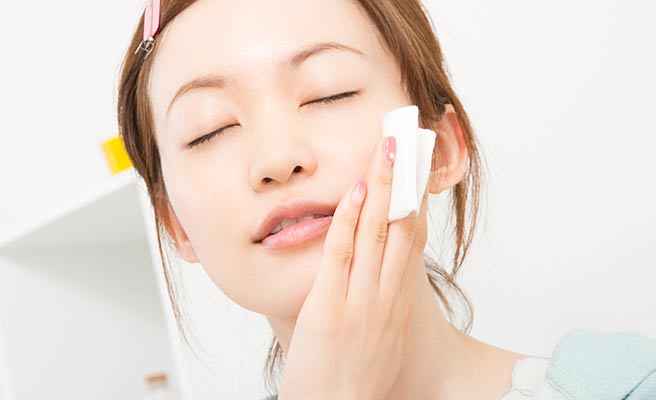 顔に美容液を当てて肌の手入れをする女性