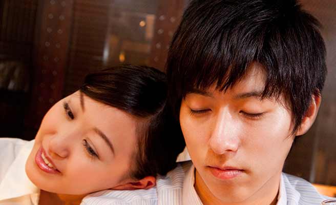 男性の肩にもたれかかる女性と目を閉じる男性