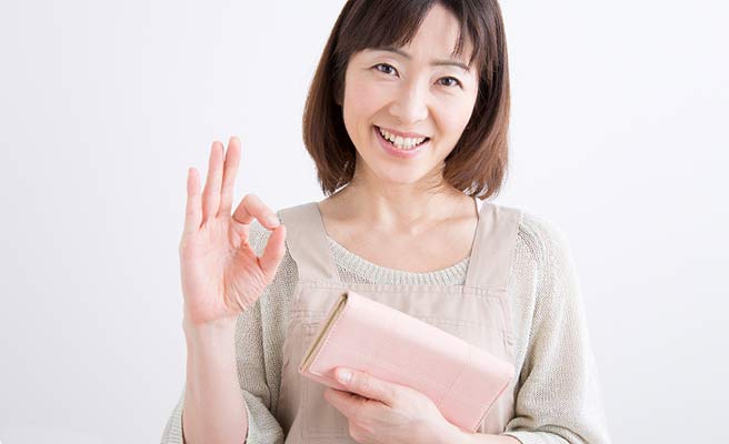財布を持ちながら指でOKサインを出す女性
