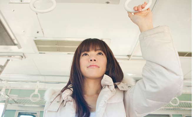 電車内でつり革につかまって立つ女性