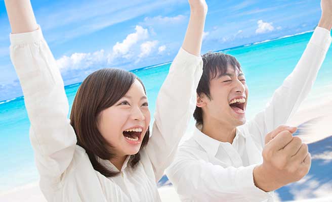 海を背景に歓喜するカップル