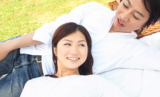 恋人と芝生に寝そべる女性