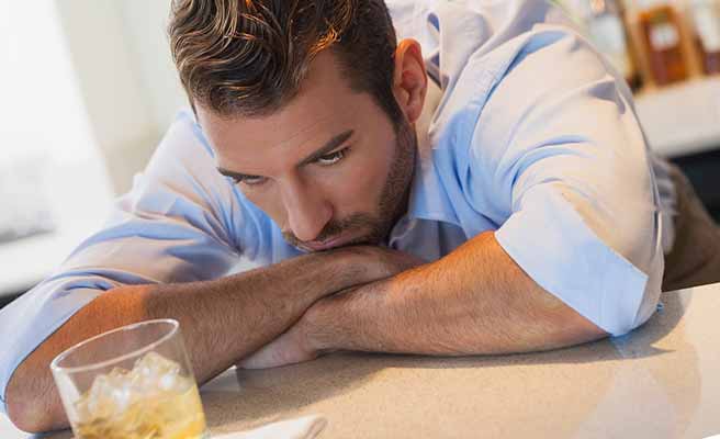 お酒を飲みながら考え込む男性