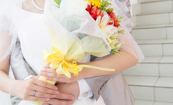 花束を持つ花嫁を抱きしめる新郎