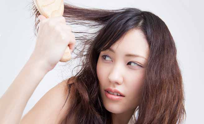 髪の毛を面倒くさそうにブラッシングする女性
