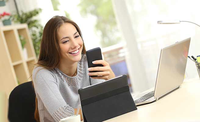 ノートパソコンとスマホを見ながら仕事する女性