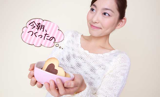 入れ物にクッキーを入れて差し出す女性