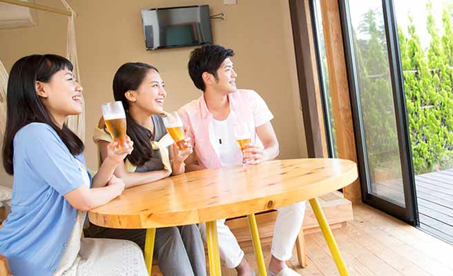 女友達と男性が一つテーブルでビールを飲んでいる