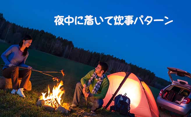 夜のキャンプ場でたき火で食事するカップル