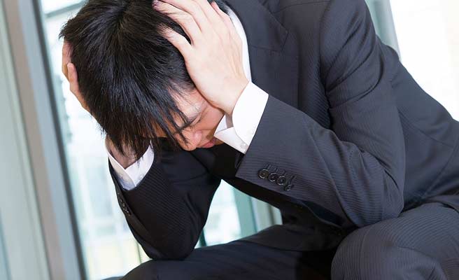 スーツ姿の男性が頭を抱える