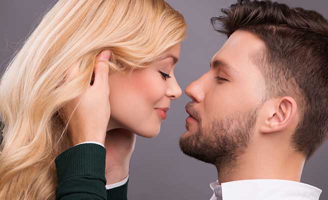 彼女の頭に手を当ててキスしようとする男性