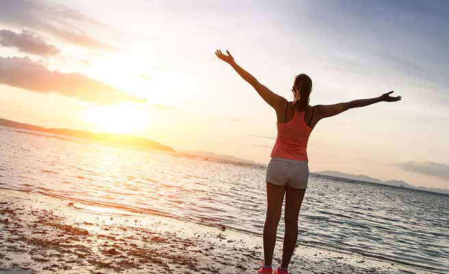 海に向かって一人両手を広げる女性