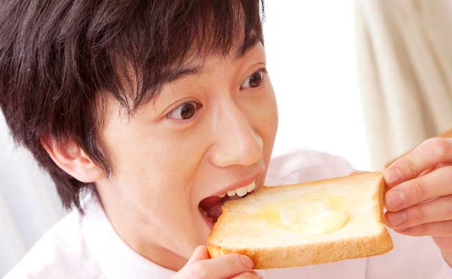 笑顔でトースト食べている男性