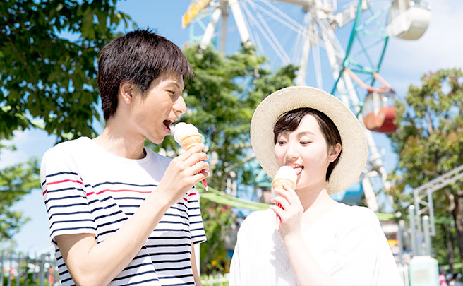遊園地でアイスを食べるカップル