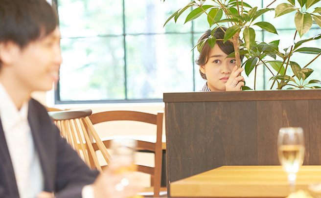 隣の席で食事する男性を影から見てる女性