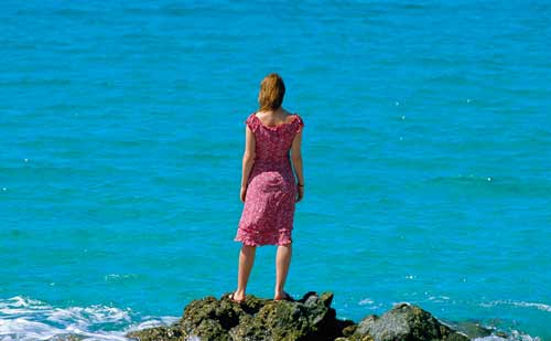 海で遠くを見つめる女性
